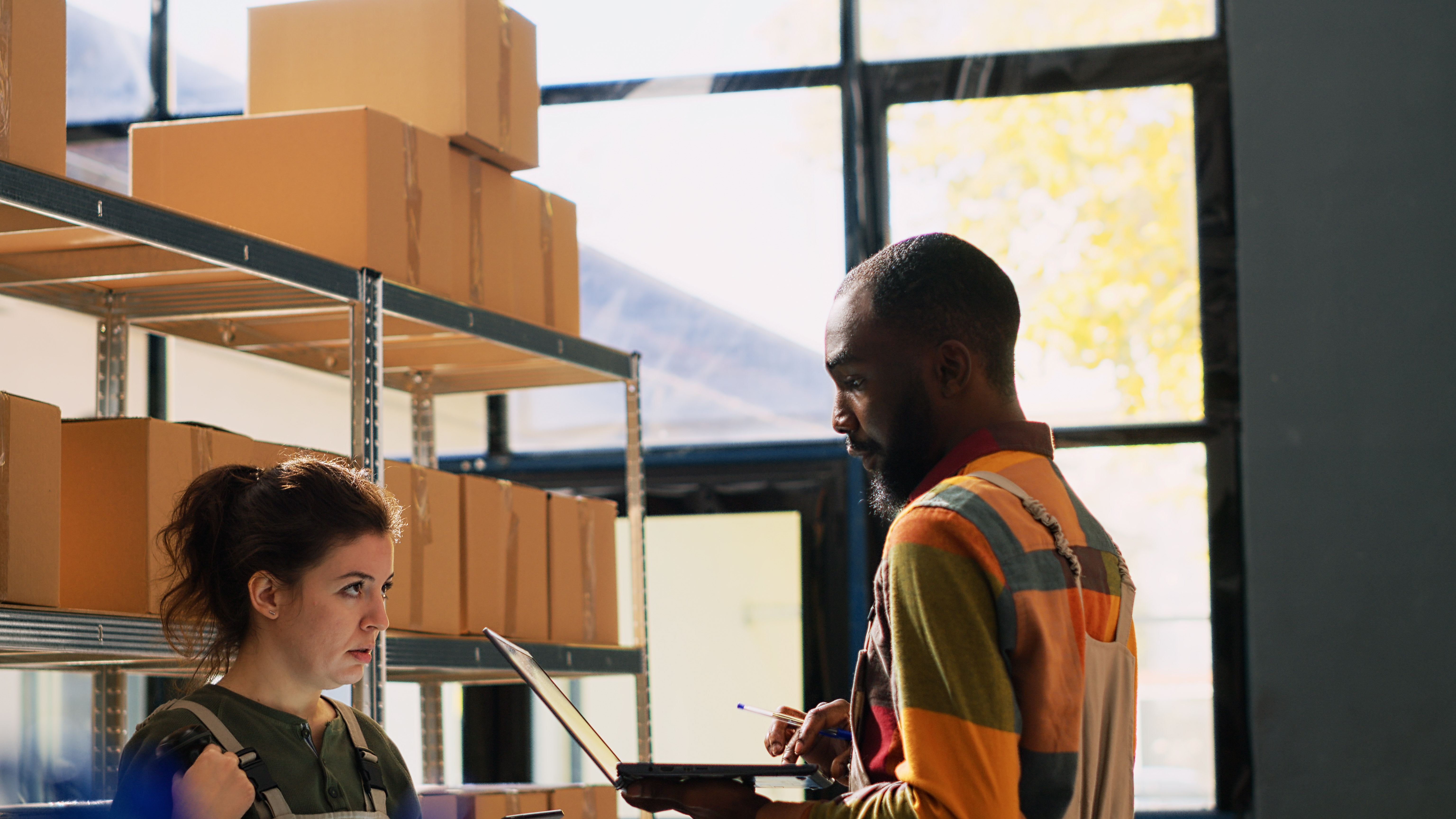 Warehouse team reviewing goods in packs, organizing products boxes before retail store orders for distribution. Diverse colleagues working in depot space, stock logistics. Handheld shot.